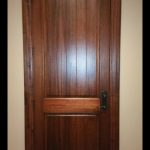 A door with wood paneling and a black handle.