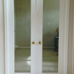 A white door with two glass panels and gold handles.